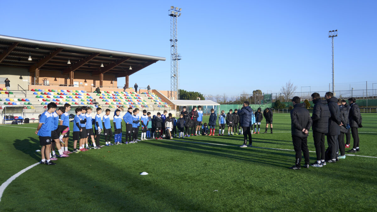 Imagen de un campus de fútbol organizado por EliteFootball con el equipo de entrenadores dando instrucciones a los jóvenes jugadores