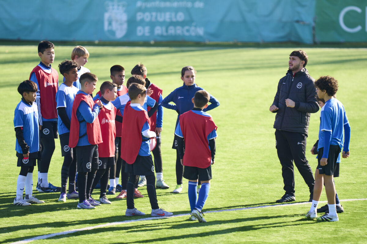 Imagen de un entrenador de EliteFootball dando instrucciones a un grupo de jugadores en un campus de fútbol